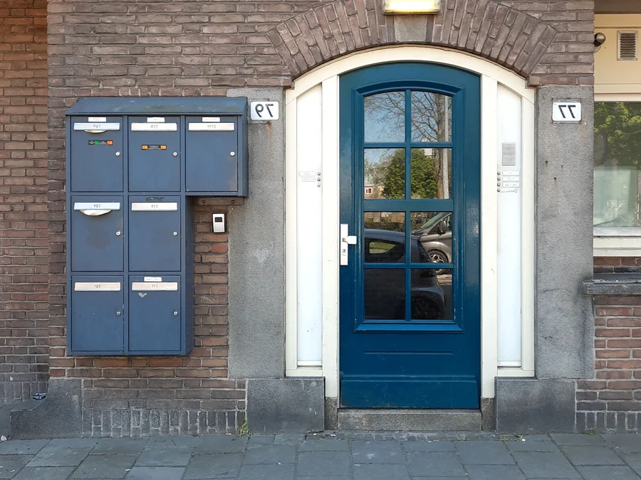 Hall d'entrée d'un immeuble bruxellois, porte vitrée et interphone — serrurier à Forest