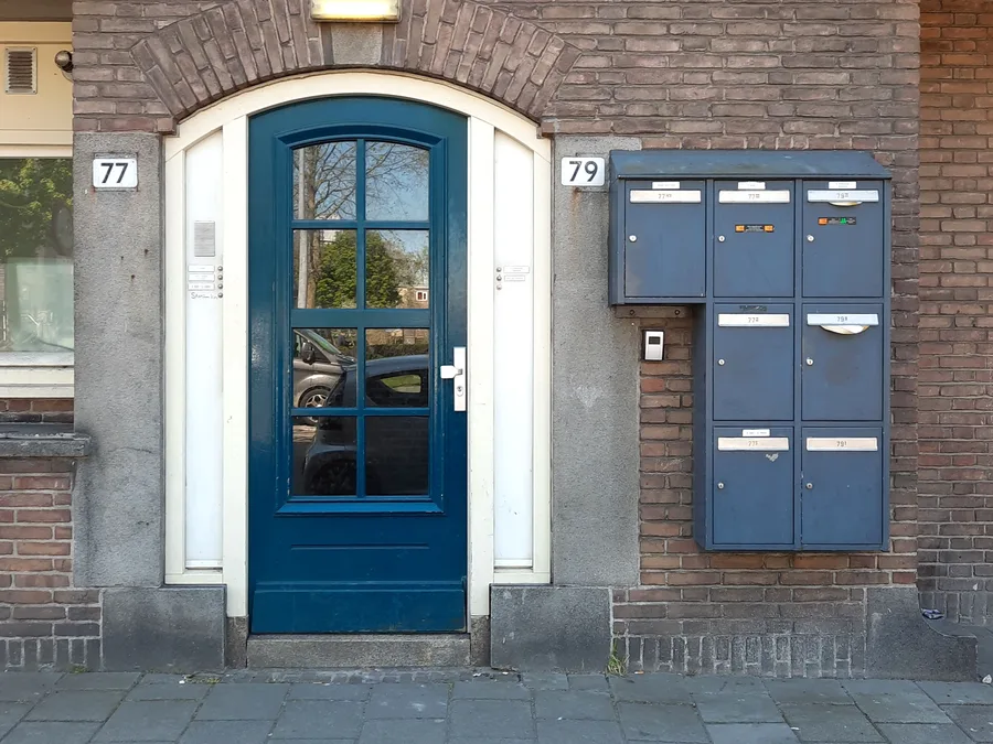 Hall d'entrée d'un immeuble bruxellois, porte vitrée et interphone — serrurier à Ganshoren