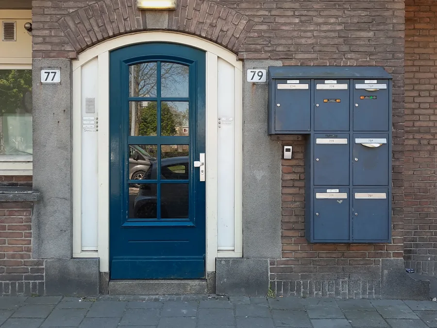 Hall d'entrée d'un immeuble bruxellois, porte vitrée et interphone — serrurier à Ixelles