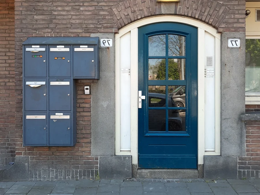 Hall d'entrée d'un immeuble bruxellois, porte vitrée et interphone — serrurier à Saint-Gilles